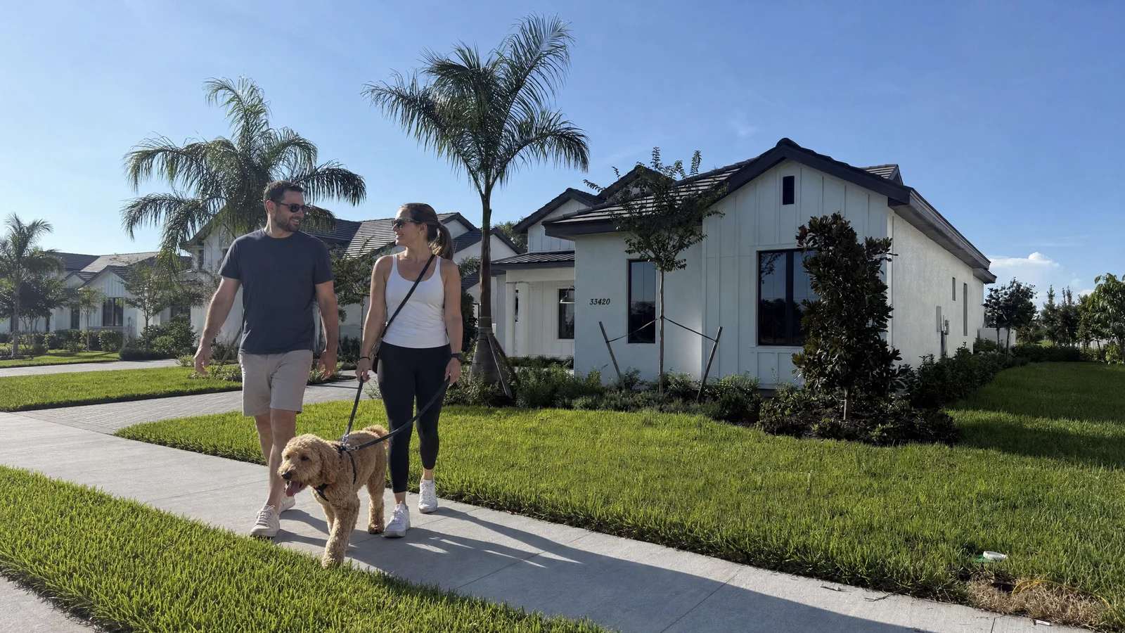 A couple walking their dog beside a palm-lined Soleta home
