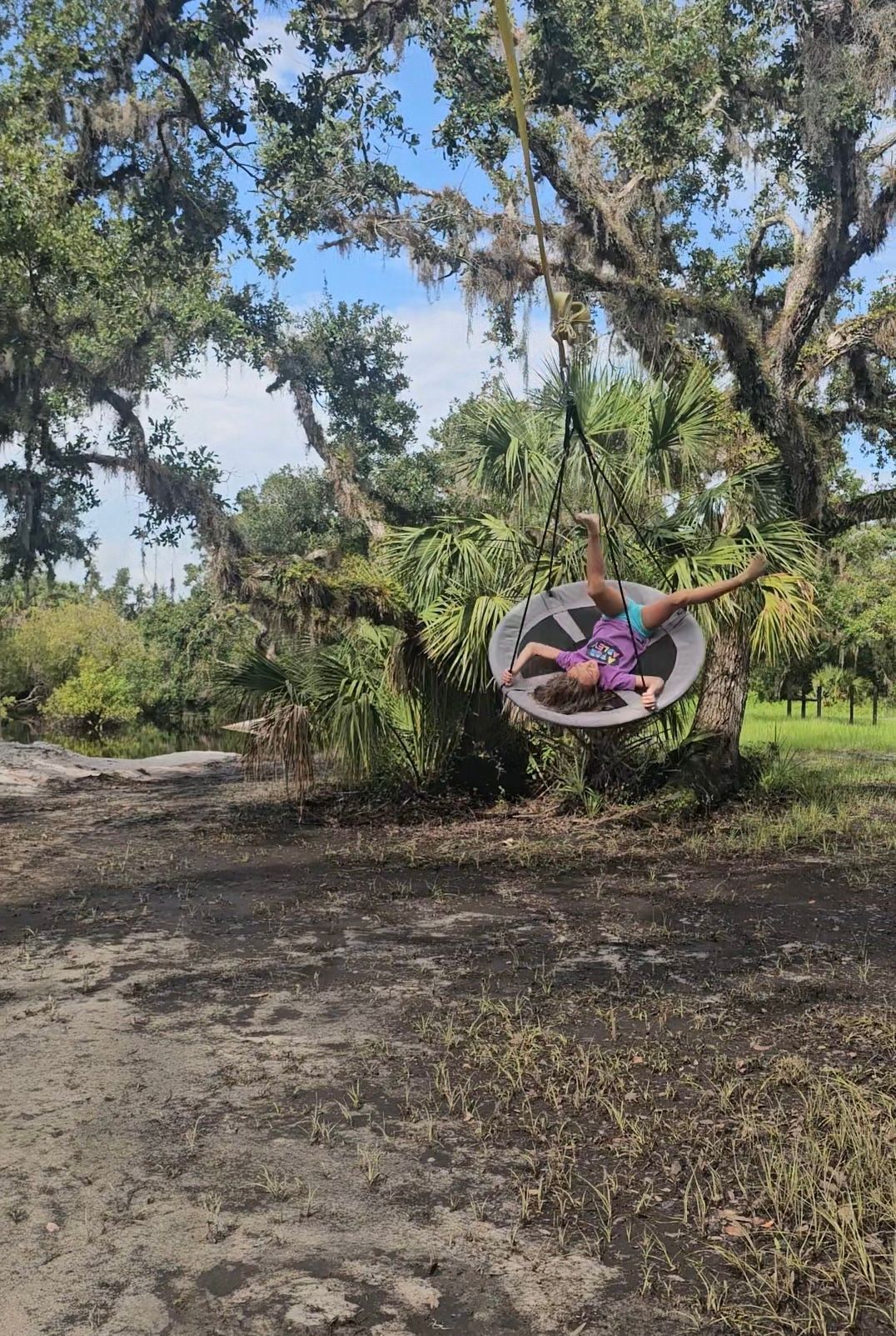 A young woman relaxing on a swing beneath the oaks at Soleta